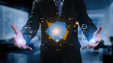 Profesyonel bir işadamı modern bir ofiste holografik görseller kullanarak ileri veri analizi sergiliyor. Bu görüntü iş iletişimindeki yenilik ve teknolojiyi vurguluyor. Dörtgen