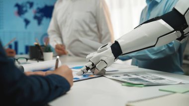 Bir robot el, çağdaş bir ofis ortamında veri analizi ve strateji geliştirmeye odaklanan bir iş toplantısında insan profesyonellere yardım eder. Noogenesis
