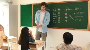 Attractive girl raised his hand and volunteer to write answer on blackboard. Teacher ask for volunteering to answer question while skilled student receive chalk and walk in front of class. Pedagogy.