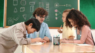 Zeki öğretmen, çeşitli çocuklar sınıf çalışması yapmak için birlikte çalışırken farklı çocukların zihin haritası çizdiği fikri açıklıyor. Çekici eğitmen öğretmek ve çalışmak hakkında konuşmak. Pedagoji.