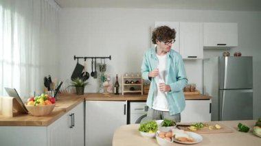 Mutlu baba yemek pişirirken müziğe geçiyor ve modern mutfakta öğle yemeği hazırlıyor. Aktif baba, sebze ve mutfak gereçleri ile çevrili sağlıklı yemek ya da salata yaparken şarkıyla dans ediyor. Pedagoji.