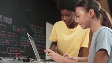 Tatlı kız dizüstü bilgisayar kodlaması yazarken ya da mühendislik sistemini programlarken mutlu Afrikalı çocuk ekranı işaret ediyor. BTMM teknoloji sınıfında dizüstü bilgisayar tutarken öğretmen eğitim programı. Öğretim