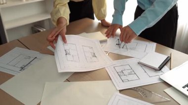 Mimarlık ve güvenlik mühendisi, modern ofiste dizüstü bilgisayarda mimari belge ve ahşap blokla sergilenen planlar hakkında tartıştı. - Yakın çekim. Tanımlama.