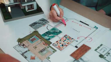 Bu resim, renk örnekleri ve tasarım fikirleriyle çevrili ayrıntılı kat planlarını çizen ellerin yer aldığı işbirlikçi bir iç tasarım planlama oturumu yakalar. SACTR