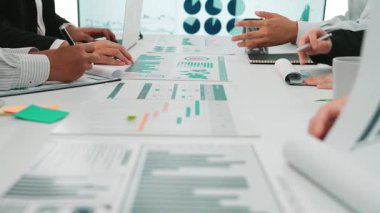 Modern bir çalışma alanında veri kavrayışlarını tartışırken finansal tablolar ve grafiklerle uğraşan profesyonel elleri gösteren dinamik bir iş toplantısı. SACTR