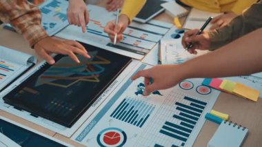 Profesyoneller, modern ofis ortamında bilgilendirilmiş kararları yönlendirmek için grafikler ve dijital cihazlardan yararlanan işbirlikçi bir veri analiz oturumuna katılıyorlar. SACTR