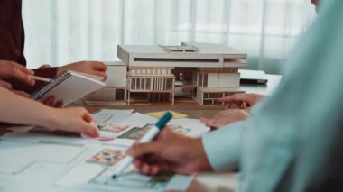 Çeşitli bir ekip, modeller ve çizimlerle çevrili, modern bir çalışma alanında yaratıcılığı ve yeniliği teşvik eden işbirlikçi bir mimari tasarım oturumuna girişiyor. SACTR