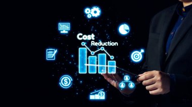 Maliyet azaltma stratejileri ile ilgili dijital simgeler ve grafikler sergilenen bir tabletle ilgilenen bir işadamı, mali iyileşme ve iş büyümesini vurguluyor. Dörtgen