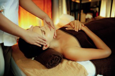 Beyaz kadın stres önleyici kafa masajı yapmaktan ve lüks otel veya otelde sıcak mum ışığında yüz güzelliği eğlencesi yapmaktan zevk alıyor. Sessiz.