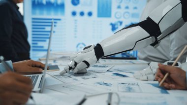 Fütürist robotik bir el, veri sunumu ve grafik ve grafiklerle analiz yoluyla işbirliğini gösteren, parlak bir çalışma alanında insan meslektaşlarıyla etkileşim içindedir.