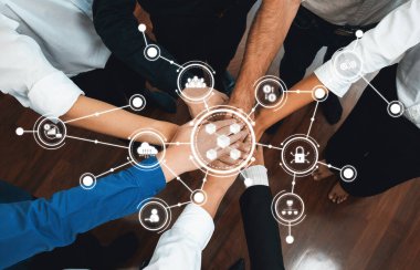 Bu görüntü, çeşitli ellerin birleşmesiyle güçlü bir işbirliği anını yakalar. Takım çalışmasına odaklanmış modern bir işyerindeki işbirliği ve bağlantıyı sembolize eder. Dostluk