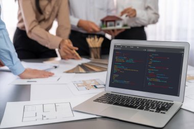 İç mimar tasarımcı grubu, daha kesin tasarım için planlar ve dizüstü bilgisayar ekran mimari yazılımı üzerinde birlikte tartışıyorlar. Modern ev tasarımı ve yenileme. İçgörü