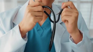 Hasta klinikte ya da hastane ofisinde doktor randevusuna gidiyor. Hastaların nabzını steteskopla kontrol edip risk faktörünü belirleyen doktor semptomları inceliyor. Ağır çekim. Katı.