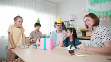 Çekici aile, modern mutfakta masaya konmuş renkli balonla süslenmiş bir şekilde konuşurken kızının doğum gününü kutluyor. Mutlu Asyalı kız gülümseyen ailesiyle pasta yiyor. Pedagoji.
