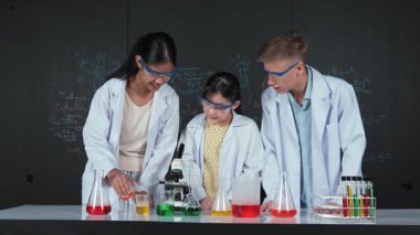 Zeki kız deney yapmak için heyecanlanan çeşitli öğrenciler iken beher kabına renkli solüsyon döker. Profesyonel bilim adamı kimyasal teoriyle kara tahtada deney yapmaya hazırlanıyor. Öğretim