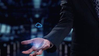 Bulut hesaplama teknolojisinin dinamik bir temsili, bir iş adamı eli ve parlayan dijital simgelerin yer aldığı, veri transferini ve güvenliği modern bir ortamda sembolize eden. Dörtgen