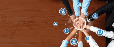 Çeşitli profesyonellerden oluşan bir grup, modern iş dünyasındaki verimlilik ve başarıyı artırma stratejileri ile ilgili takım çalışmasını ve işbirliğini simgelemek üzere el ele veriyor. Dostluk