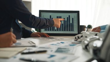 Dinamik bir iş toplantısı, veri analizinde yer alan profesyonellerin bilgisayar monitöründe gösterilen grafiklerle trendleri vurguluyor. Noogenesis