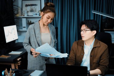 Satış müdürünün dizüstü bilgisayarında çalışan ciddi bir yüz, sekreterin gece geç saatlerde fazla mesai belgelerini verirken yönetim kurulu şirketinin veri tabanında dosya tutması için imza topluyor. İnfobahn.