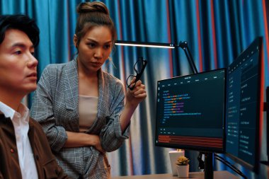 Bilgi teknolojisi geliştiricileri modern ofisteki neon ışık odasında verileri çevrimiçi olarak çalıştıran akıllı web sitesi geliştirme kodlayıcı sistemine işaret ediyorlar. İnfobahn.