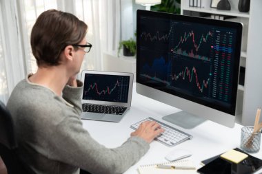 Bilgisayar ve dizüstü bilgisayarı kullanarak, çalışma masasındaki dinamik artırılmış borsa grafiğinin en yüksek kar değerini araştıran bir tüccar, modern ofisteki ekrandaki döviz kuru değerini analiz ediyor. Bireysel.