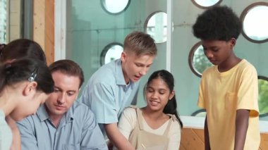 Akıllı robotlar sınıfta dizüstü bilgisayar ekranını işaret ederken, beyaz bir öğretmen yorum yapıyor ya da öğrencilere tavsiye veriyor. Öğretmen bilgisayar kullanırken çeşitli öğrencilerin ders verirken not alması. Öğretim