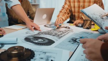 Bir grup mühendis, takım çalışmasını ve yenilikçi çözümleri vurgulayarak modern bir çalışma alanındaki plan ve prototipleri kullanarak çoklu mekanik tasarımlar üzerinde işbirliği yapmaktadır. SACTR