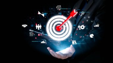 Bir işadamı, dijital pazarlamada büyümeyi ve başarıyı simgeleyen, analitik ve teknoloji yoluyla yenilikleri gösteren bir holografik hedefi bir okla güvenle sunar. Dörtgen