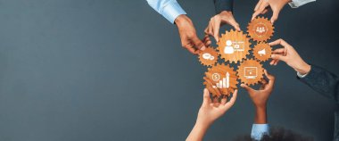 Bu resim, çeşitli iş kavramlarını sembolize eden, dijital bir ortamda işbirliği ve yeniliği vurgulayan vitesleri bir arada tutan elleri gösteriyor. Dostluk