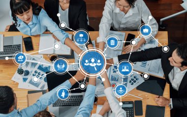 Modern bir ofis ortamında çeşitli profesyoneller arasında iş birliği ve veri görselleştirmesini gösteren dinamik bir iş toplantısı. Takım çalışmasını ve yenilikleri vurguluyor. Dostluk