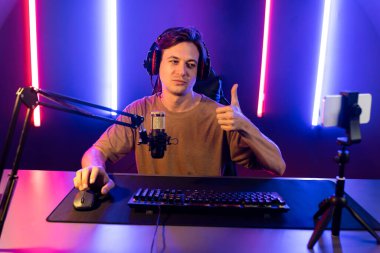 Oyun kanalı, online oyun oynayan akıllı flamalı oyun sunucusu, kulaklık takan, neon ışıklandırma odasındaki takım oyuncusuyla akıllı telefondan canlı yayında konuşan izleyiciler. Bireysel.