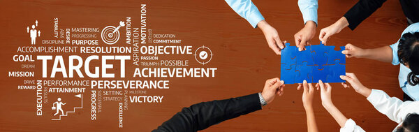 Разнообразные руки объединяются, чтобы собрать синюю головоломку на деревянном столе, окружённом вдохновляющими словами, символизирующими командную работу, цели и упорство в достижении успеха. Ах!