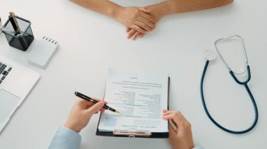 Klinikteki ya da hastane ofisindeki doktor randevusuna katılan hasta, tıbbi tedavi seçeneklerini tartışıyor ve muayene sonuçlarını ya da hastalıkla ilgili tıbbi kayıtları açıklıyor. Ağır çekim. Katı.