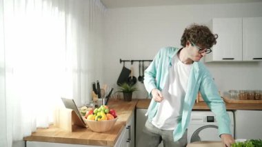 Mutlu baba yemek pişirirken müziğe geçiyor ve modern mutfakta öğle yemeği hazırlıyor. Aktif baba, sebze ve mutfak gereçleri ile çevrili sağlıklı yemek ya da salata yaparken şarkıyla dans ediyor. Pedagoji.