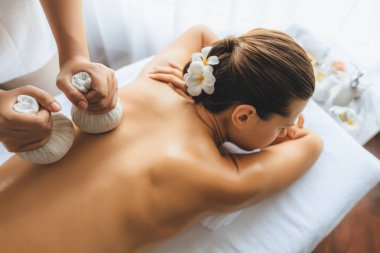 Sıcak bitkisel top spa masaj vücut tedavisi, masör kadın vücuduna nazikçe şifalı bitki torbası bastırıyor. Aromaterapi dinlenme sükuneti ve sükuneti kaplıca salonundaki atmosferi aydınlatıyor. Sessiz.