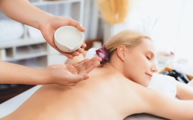 Masör elleri kadının sırtına aroma yağı döküyor. Masözler lüks otellerdeki kaplıca salonundaki müşteriler için yağ masajı prosedürü hazırlıyorlar. Aroma yağı vücut masajı konsepti. Sessiz.