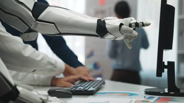 Modern bir ofiste bir robot kol, günümüzün dinamik çalışma yerinde insan yaratıcılığı ve ileri teknolojinin karışımını vurgulayan bir bilgisayarla bağlantı kurar.
