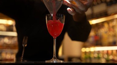 Gülümseyen Asyalı akıllı barmen, lüks tezgah barında bardakla karışık kokteyl hazırlıyor, VIP müşteriyle birlikte gece hayatı sıcak gece kulübü servisinde özel bir içecek hazırlıyor. Vinosity.