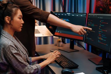 Modern ofisteki neon ışık odasında bilgi ağını gösteren dizüstü bilgisayarla iki ekranda veri çalıştıran akıllı web sitesi geliştirme kodlayıcı sistemini tartışan IT geliştiricilerinin ciddiyeti. İnfobahn.