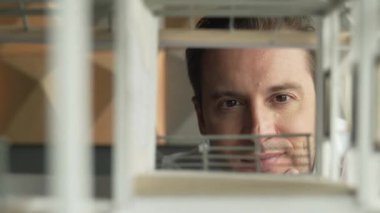 Kafkasyalı mimar mühendisinin yakın çekimi ev inşaatını denetlemek ve bina malzemelerini kontrol etmek. Proje yöneticisi modele dikkatlice bakarken kalemi işaret ediyor. Yönlendirici.