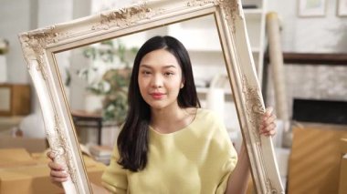 Girişimci elinde resim çerçevesi tutarken elinde nakliye siparişlerinin dağıtıldığı bir paket vardı. Asyalı satıcı kameraya özgüvenle bakıyor ve ürünü sunuyor. Myrmidon.