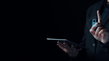 Bir kişi, veri koruması ve güvenlik teknolojisini sembolize eden canlı siber güvenlik grafiklerinin yer aldığı karanlık bir arka plana karşı akıllı telefon tutuyor. Dörtgen