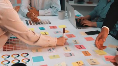 Dinamik ofis ortamı, renk ve yaratıcılıkla dolu işbirlikçi bir beyin fırtınası oturumunu gösteriyor. Bireyler yapışkan notlar, dizüstü bilgisayarlar ve canlı fikirlerle meşgul olurlar. SACTR