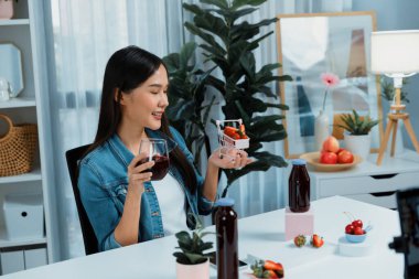 Gülümseyen, güzel Asyalı genç, lezzetli karışık çilek ve kiraz suyu detoksu içeceklerini inceleyen, sosyal medyada özel promosyon satışı için sağlıklı ürünler sergileyen. Taktik.
