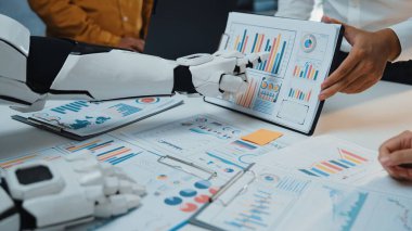 Bir insan ve robot olarak işbirliğinin geleceğini araştırın birlikte verileri analiz edin, grafikler ve grafiklerle çevrili şık bir ofis ortamında, yenilik sergiliyor.