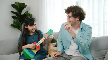 Mutlu bir babanın, ukulele çalan ve şarkı söyleyen akıllı kızına bakışının arkası. Mutlu baba motive oldu ve Amerikalı liseli kızı gitar çalmaktan zevk almaya teşvik etti. Aile eğlencesi. Pedagoji.