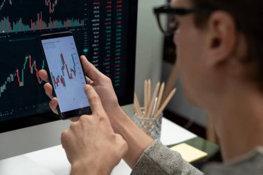 Akıllı borsa yatırımcıları ekranda akıllı telefon ile piyasa borsasını işaret ederek dizüstü bilgisayarın yanı sıra en yüksek dinamik yatırım oranını göstererek, modern işyerindeki veri planlamasına odaklanıyorlar. Bireysel.