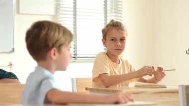 Beyaz bir çocuk ödevlerini yaparken ve açıklama dinlerken güzel bir öğretmen sınavı açıklıyor. Sınıfta not alırken ya da kağıda cevap yazarken öğretmenine bakan sevimli bir çocuk. Pedagoji.