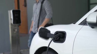 Adamın biri evinde elektrikli araç şarj aletinin fişini çekiyor. İlerici bir yaşam tarzında elektrikli araçların kullanımı, temiz ve sağlıklı bir çevreye katkıda bulunur..