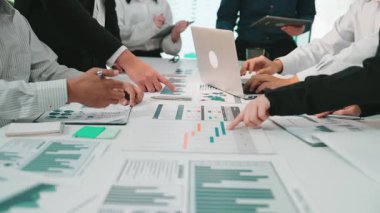 Çeşitli bir iş ekibi, dijital ekranlarda gösterilen verileri analiz etmek için işbirlikçi bir toplantıya katılıyor. Eller grafikler üzerinde hareket eder, modern ofis ortamında takım çalışmasını yansıtır. SACTR